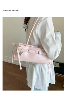 Detailed view of a pink PU leather underarm bag featuring a bow and heart pendant
