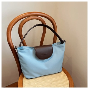 Detailed close-up of blue canvas tote bag with brown leather flap and CLEAROK logo