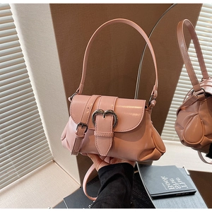 Detail of pink glossy saddle bag with heart-shaped metal buckle and wide strap