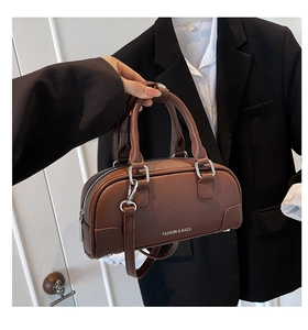 Détail d'un sac bowling en cuir marron à motif litchi avec des ferrures argentées