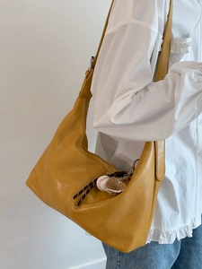 Retro yellow hobo shoulder bag with baseball charms on a minimalist background