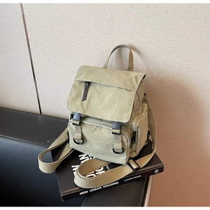 Detail view of light green nylon backpack with plastic buckles on a black sofa