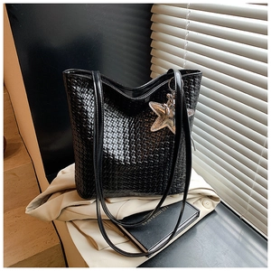 Detail of black woven texture large tote bag with silver star charm and glossy straps