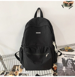 Detail view of the black minimalist nylon backpack with brand label and stripe zipper puller