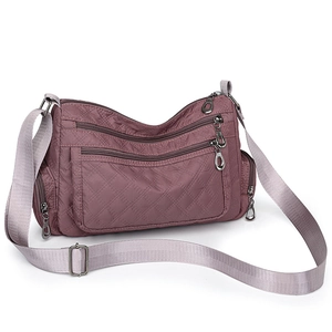 Detail view of purple quilted nylon crossbody bag featuring multi-pocket zipper compartments