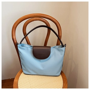Detail showing the embossed CLEAROK logo on the leather flap of the blue tote bag
