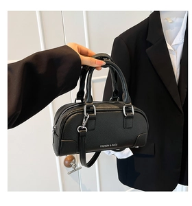 Gros plan du sac bowling noir en cuir grainé avec détails métalliques argentés