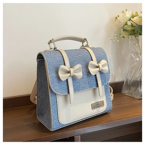 Detail of a denim college backpack with white leather trim and decorative bows