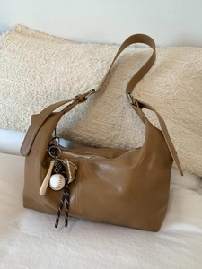 Retro camel leather dumpling shoulder bag with baseball charms on a cozy beige background