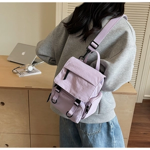 Detail view of light purple nylon backpack with flap closure and black buckle straps