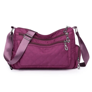 Detail view of purple quilted nylon crossbody bag featuring multi-pocket zipper design