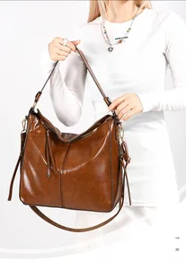Dettaglio di una borsa a secchiello in pelle marrone con cerniera a nappe e metallo dorato