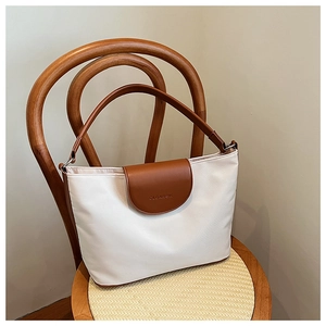 Detail of a cream and brown tote bag showing textured fabric and leather trim on a chair