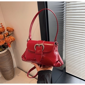 Close-up of a red saddle bag featuring a glossy finish and a silver heart-shaped buckle