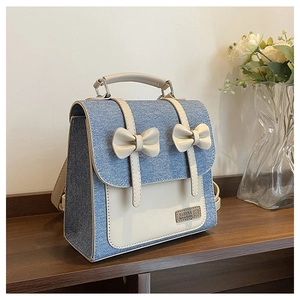 Detail of college style backpack featuring denim texture and cream leather bow decorations
