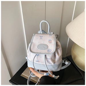 Close-up of light blue mini backpack with cartoon bear prints and leather logo patch
