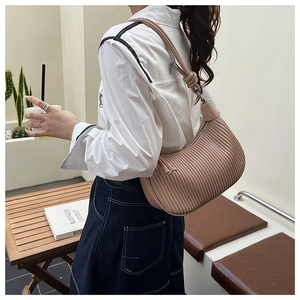 Detail of hobo bag featuring elegant pleats, knotted strap, and soft pink textured leather