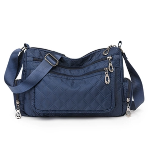 Detail view of navy blue nylon crossbody bag with quilted diamond pattern and multi-zipper pockets