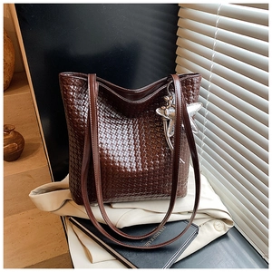 Detail of dark brown woven leather tote with star charm and zip closure texture