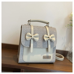 Detail of grey canvas backpack featuring leather patchwork and decorative bows