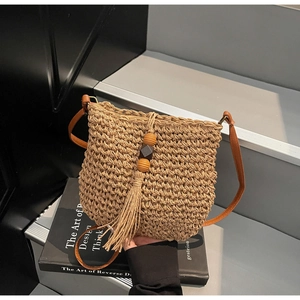 Dettaglio della borsa a tracolla in paglia intrecciata con perle in legno e cuoio