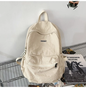 Detail of off-white canvas backpack showing the brand label and high-capacity storage design