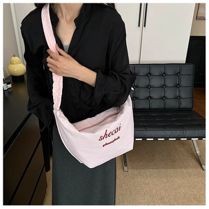 Detail of pink pleated cloud bag with red text logo and adjustable shoulder strap