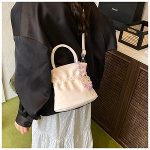 Detail of cream white pleated shoulder bag with decorative purple and white bead chain