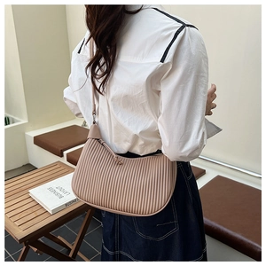 Detail view of the beige pleated hobo bag with a minimalist half-moon shape and shoulder strap