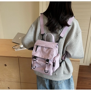 Rear view of model wearing a lavender nylon mini backpack with side pockets and zippers
