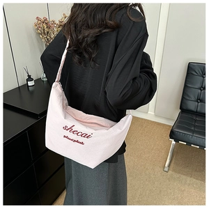 Detail showing the pink crescent bag with red embroidery lettering worn over the shoulder