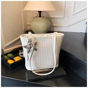 Detailed view of white woven tote bag texture with a silver starfish charm accessory