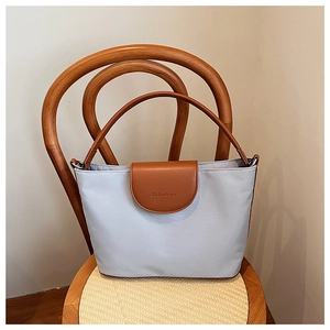 Detail of light blue tote bag featuring brown leather flap and CLEAROK brand embossing