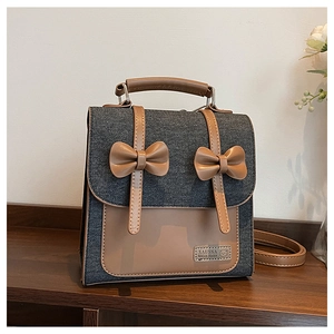 Detailed close-up of the vintage grey denim backpack with leather bows and metal logo