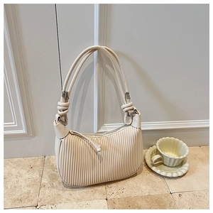 Close-up detail of cream pleated dumpling bag featuring knot handle and smooth zipper