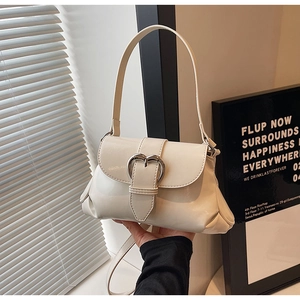 Detail of white patent leather baguette bag with silver heart buckle and side pleats