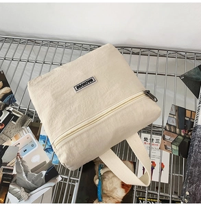 Detail view of the beige canvas backpack showing the metal zipper and top handle