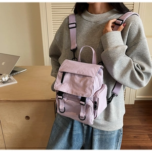 Detail of lavender mini backpack featuring flip-top buckle and side zipper pockets