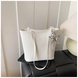 Close-up of white woven leather bucket bag featuring a detachable silver star pendant charm
