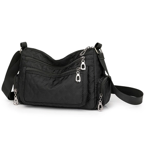Detail of black quilted nylon crossbody bag featuring multiple zipper pockets and silver rings