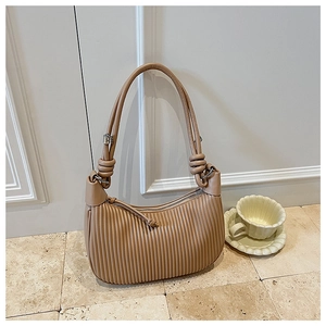 Close-up of pleated texture and knotted shoulder strap detail on khaki bucket bag