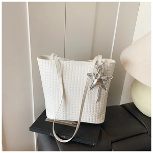 Detail of white woven bucket bag featuring a silver sequin star charm for daily commute
