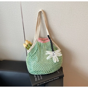 Detail of green mesh crochet shoulder bag with pink trim and white daisy charm accessory