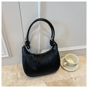 Detail of black pleated croissant bag featuring silver ball charm and knotted handle