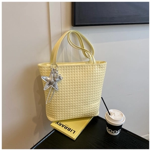 Detailed view of woven texture on yellow bucket bag with silver star charm and strap