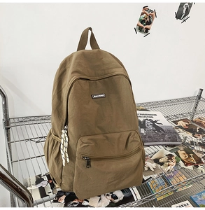 Detail of khaki canvas backpack with zippered front pocket and brand logo displayed