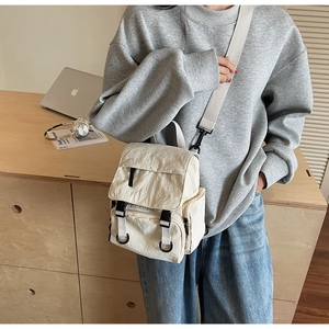 Lifestyle view of cream nylon multipurpose backpack with adjustable wide shoulder straps