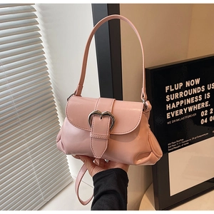 Close-up of pink saddle bag with heart-shaped metal clasp and ruched side details