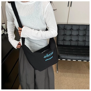 Detail of black dumpling crossbody bag with blue embroidery in a modern home interior