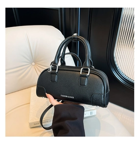 Détail du sac à main en cuir grainé noir avec texte blanc et poignées supérieures